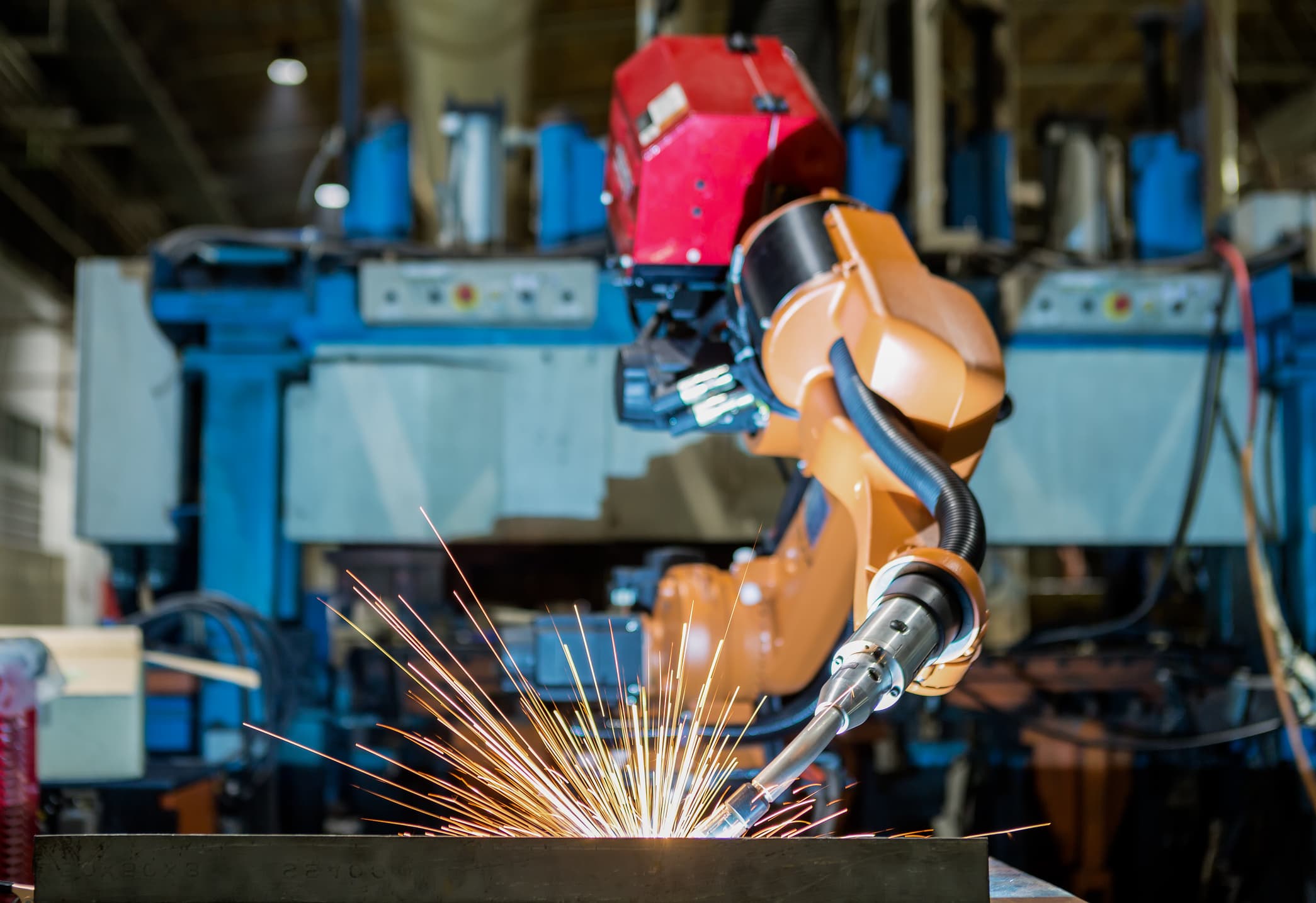 Industriell sveiserobot som arbeider på en stålkonstruksjon i en produksjonshall